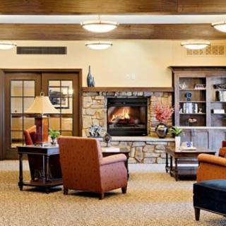A cozy lounge with a fireplace, comfortable seating, and a bookshelf.