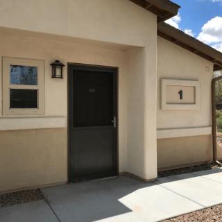 A residential building entrance with a black door and windows.