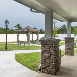 A well-maintained garden with a covered patio, stone columns, and a gazebo.