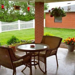 Cozy patio with wicker furniture overlooking a lush garden.