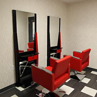 A modern hair salon featuring stylish red chairs and large mirrors.