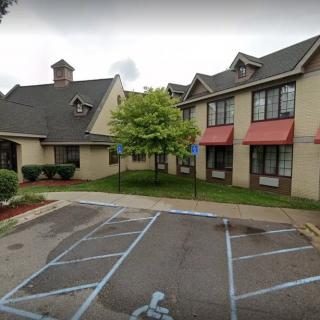 A view of a building with a parking lot and landscaped areas.
