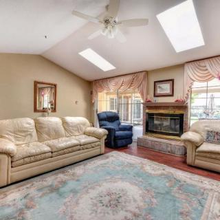 A cozy living room with a sofa set, fireplace, and skylights.