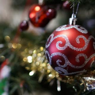 A beautifully decorated Christmas tree ornament in vibrant red with silver swirls.