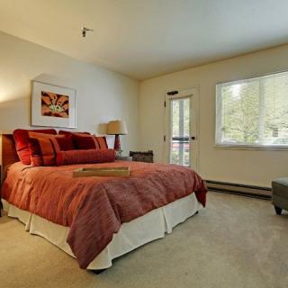 A cozy bedroom featuring a large bed with red bedding, a window, and tasteful decor.
