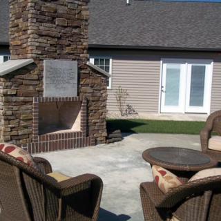A cozy backyard patio featuring a stone fireplace and comfortable seating.