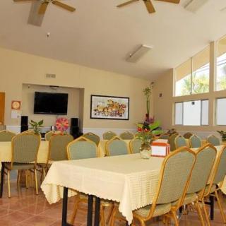 A well-lit conference room with arranged tables and chairs, featuring a television and decorative elements.