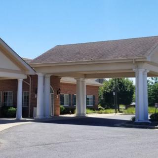 A building with a covered entrance supported by columns and an adjoining driveway.