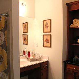 A cozy bathroom with framed art and a wooden cabinet.
