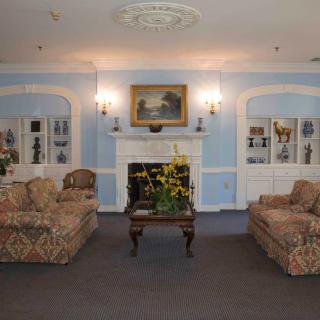 A traditionally styled living room with sofas, a coffee table, and a fireplace adorned with wall art and decorative molding.