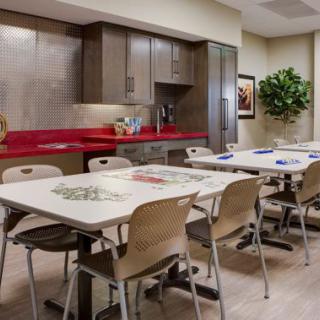A modern kitchen and dining area with tables, chairs, and cabinetry.