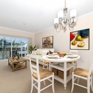 A bright dining room with a white table and chairs, complemented by artwork and a chandelier.