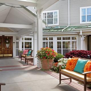 A welcoming building entrance with benches adorned with colorful cushions and vibrant potted flowers.