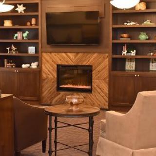 A cozy living room with a fireplace, television, and comfortable seating surrounded by built-in shelves.