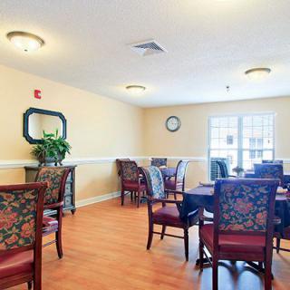 A cozy dining room with floral upholstered chairs and round tables under soft lighting.
