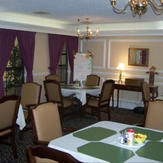 An elegantly decorated dining room with a table and chairs, featuring a chandelier and purple curtains.