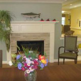 A cozy living room with a fireplace and a vibrant flower arrangement.