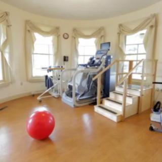 A home gym featuring a treadmill and a red exercise ball in a bright, well-lit room.