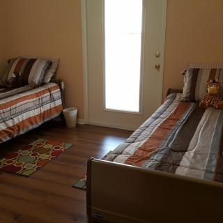 A cozy bedroom with twin beds featuring striped bedding, wooden floor, and a door leading outside.