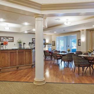 A cozy dining area with several tables and chairs, featuring a wooden floor and elegant decor.