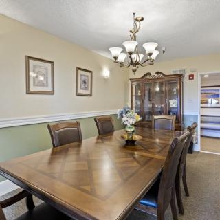 A well-decorated dining room featuring a large wooden table, cushioned chairs, a china cabinet, and an elegant chandelier.
