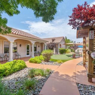A beautiful residential property featuring a landscaped garden with trees, a walkway, and patio areas.