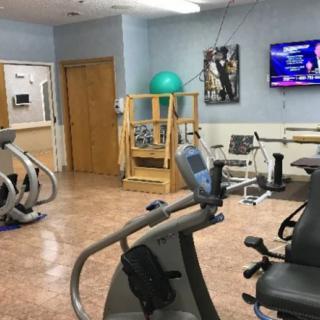 A fitness room equipped with various exercise machines and a television.