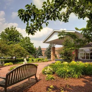 A peaceful garden area with a bench and lush greenery in front of a building.