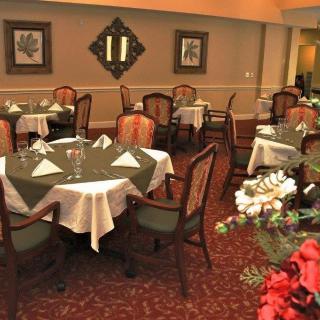 An elegant dining room setup with neatly arranged tables and chairs, complemented by decorative flowers and artwork on the walls.