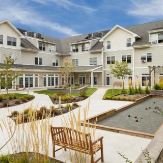 A modern residential building featuring a landscaped courtyard with pathways and outdoor seating.