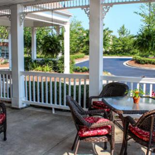 A cozy porch with wicker chairs and a table, offering a relaxing garden view.