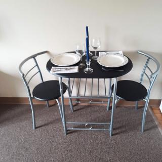 A small dining table set for two with plates, a wine glass, and a candle.