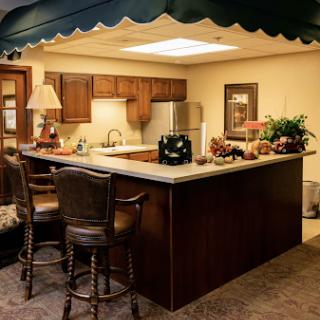 A cozy kitchen area featuring a central island with bar stools, wooden cabinetry, and decorative elements.