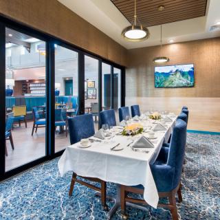 An elegantly set dining table in a restaurant with blue chairs and stylish decor.