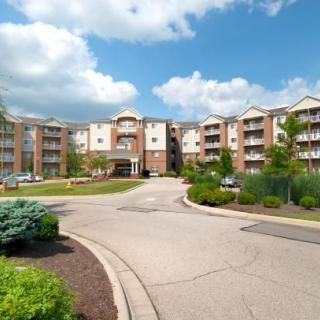 A modern apartment complex with well-maintained landscaping under a partly cloudy sky.