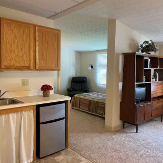 A cozy studio apartment featuring a kitchenette, living area, and bedroom space.