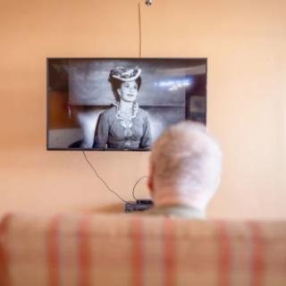 A person watching a vintage black and white movie on a television.