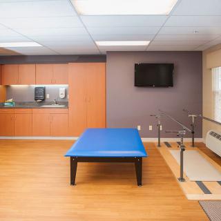 A rehabilitation room equipped with a therapy table and parallel bars for physical therapy exercises.