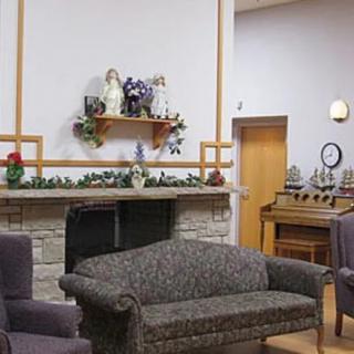 A cozy living room with a sofa, decorated mantelpiece, and an organ in the corner.