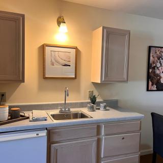 A modern kitchen setup with wooden cabinets, a sink, and framed artwork on the wall.