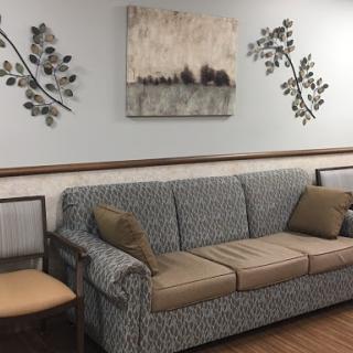 A cozy living room setup featuring a patterned couch with throw pillows, complemented by wall decor and artwork.