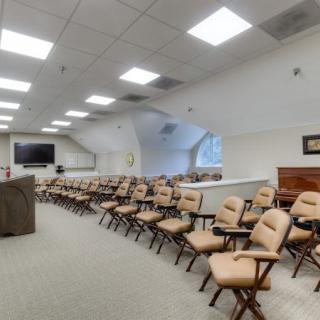 An empty conference room with rows of beige chairs arranged neatly, ready for a meeting or lecture.