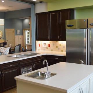 A modern kitchen featuring dark cabinetry, a central island with a sink, and stainless steel appliances.