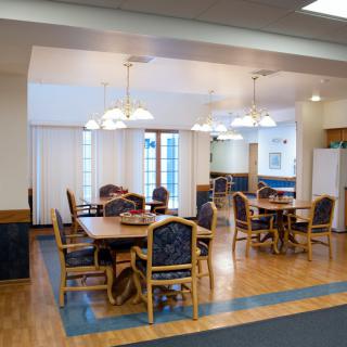 A spacious dining area with wooden tables and chairs, illuminated by overhead lighting.