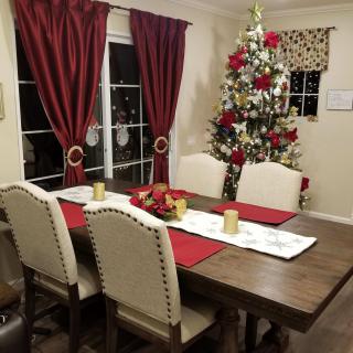 A cozy dining room decorated for Christmas with a festive tree and elegant table setting.