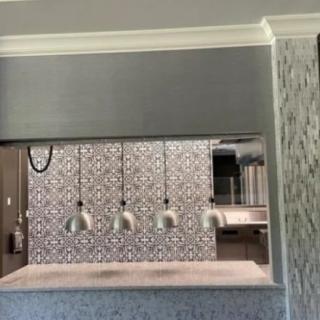 A modern kitchen interior featuring patterned tiles and sleek pendant lights over a countertop.