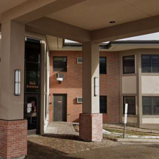 A view of a building exterior with columns and brickwork at the entrance.