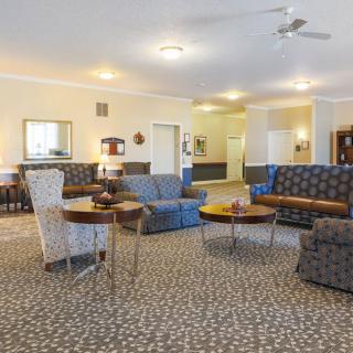 A spacious living room featuring multiple seating arrangements with sofas and round tables on a carpeted floor.