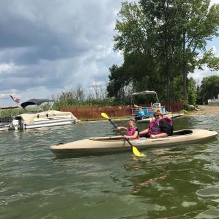 A group of people kayaking on a lake surrounded by trees and other boats.