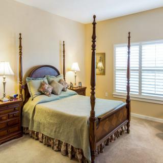 A cozy bedroom featuring a four-poster bed and two nightstands with lamps.